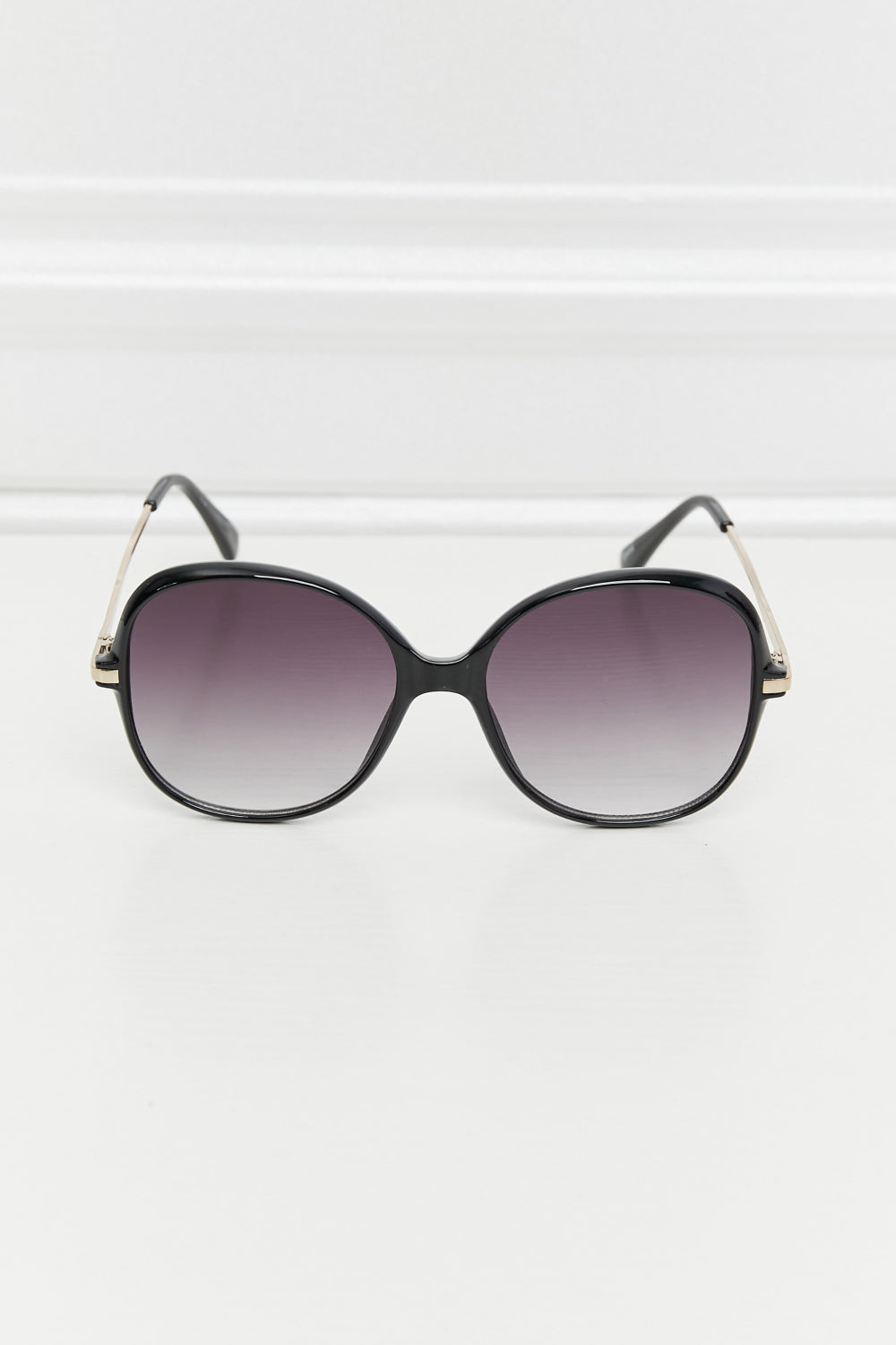 Oversized round black sunglasses with gradient lenses and gold accents on the temples.