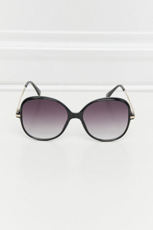 Oversized round black sunglasses with gradient lenses and gold accents on the temples.