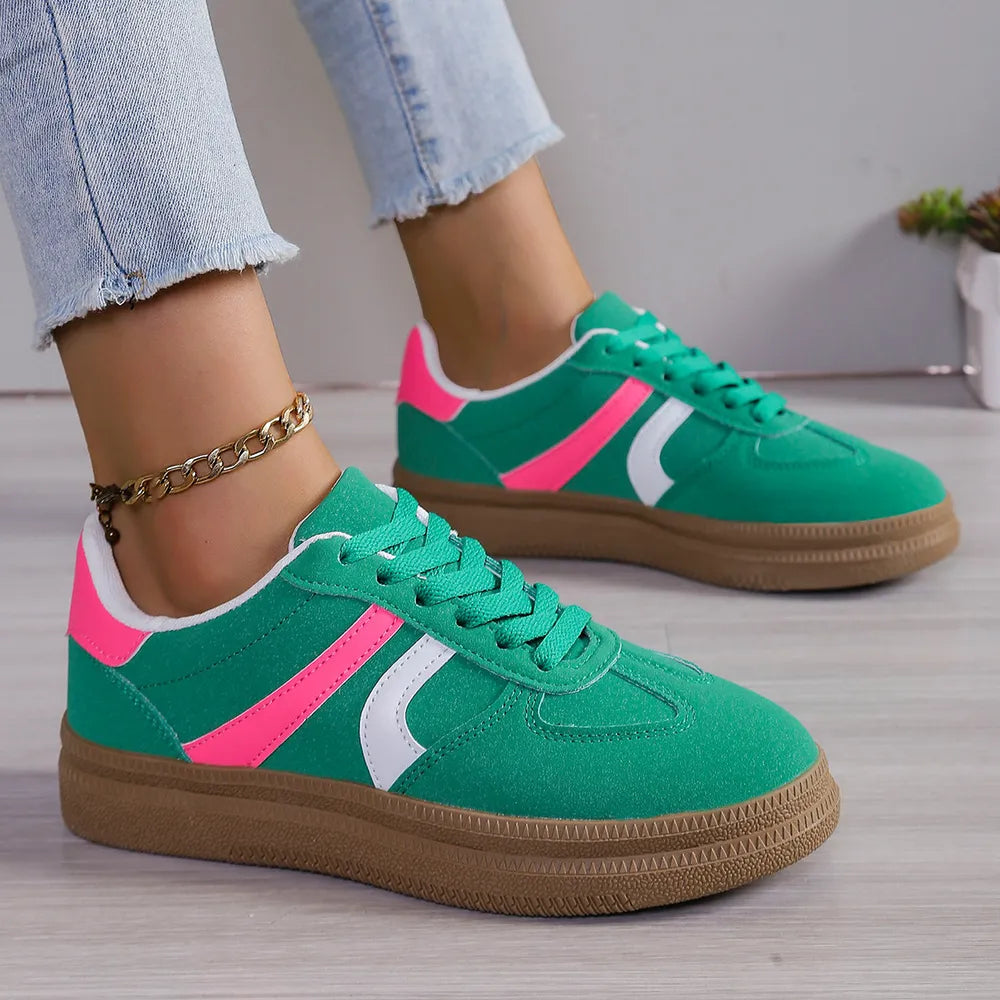 Green suede platform sneakers with pink and white curved stripes and gum soles.
