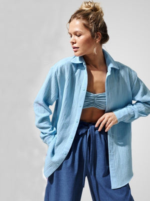 Light blue textured cotton overshirt with relaxed fit and button front, styled open over a bralette.