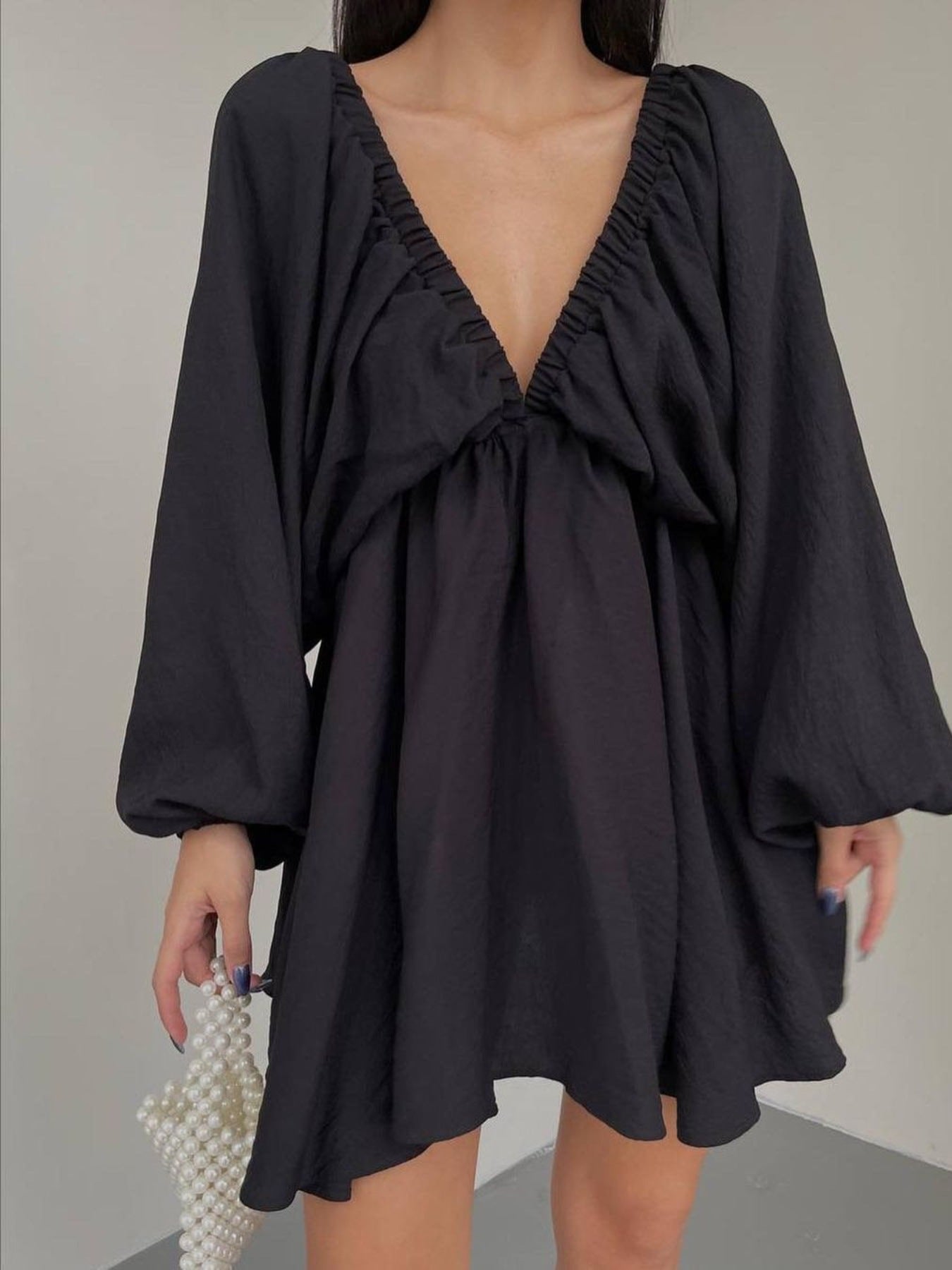 Black ruched V-neck dress with balloon sleeves and a flowy skirt.