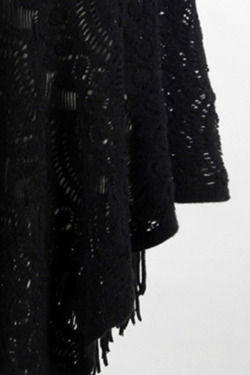 Black crochet poncho with open knit pattern and fringe detail