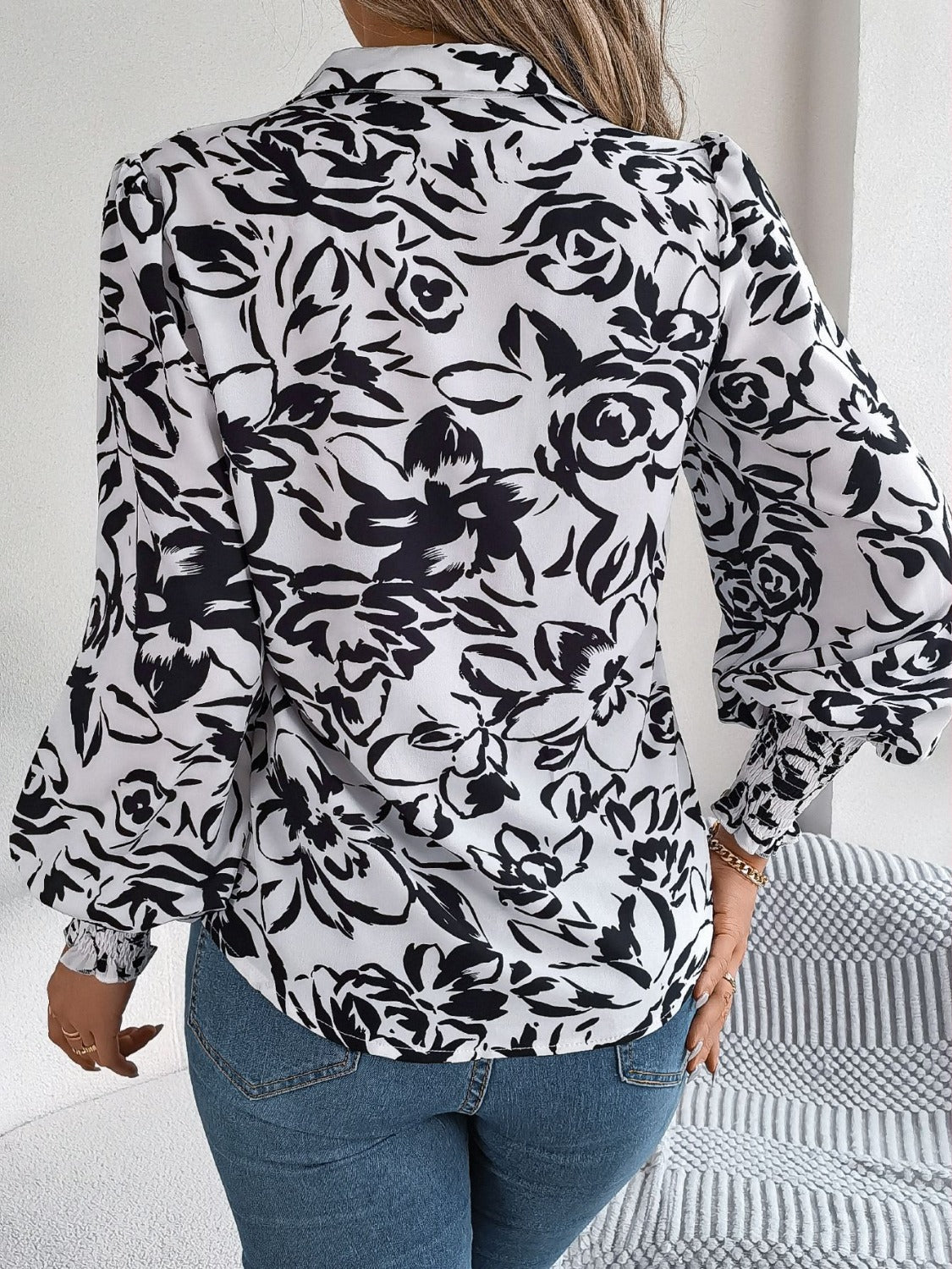 White floral print blouse with shirred cuffs and buttoned front detail.