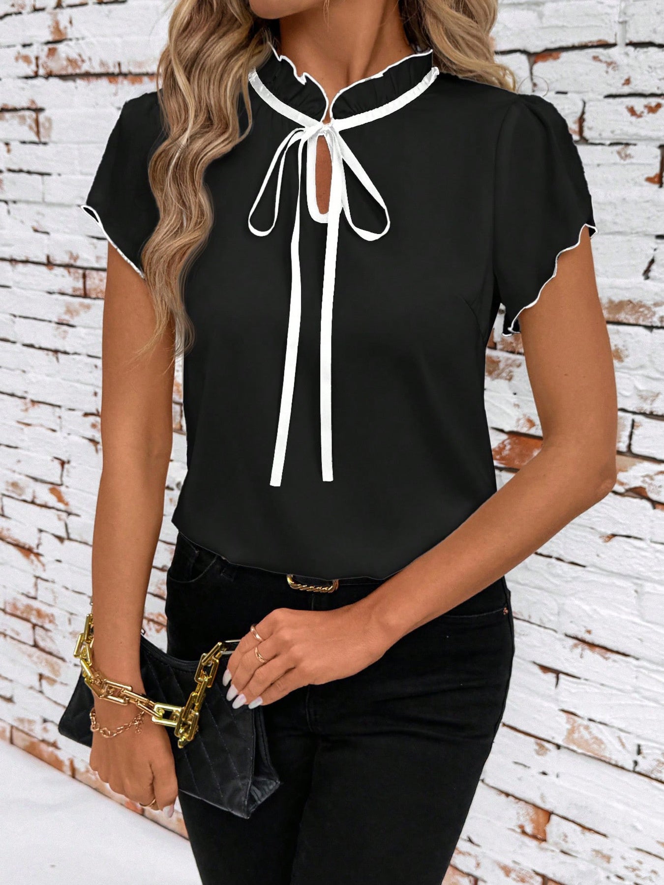 Black maternity blouse with white trim, tie-neck, and ruffled collar.