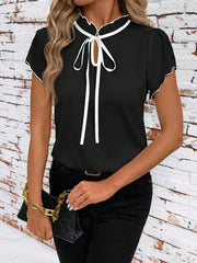 Black maternity blouse with white trim, tie-neck, and ruffled collar.