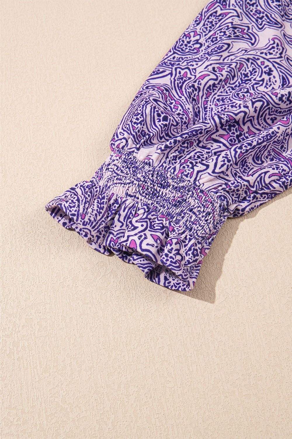 Paisley print blouse in lavender with smocked cuff and ruffled hem detail.