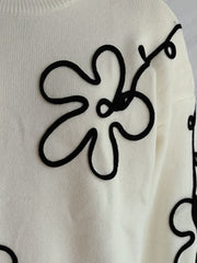 Beige knit sweater with black floral outline embroidery, crew neck, long sleeves.