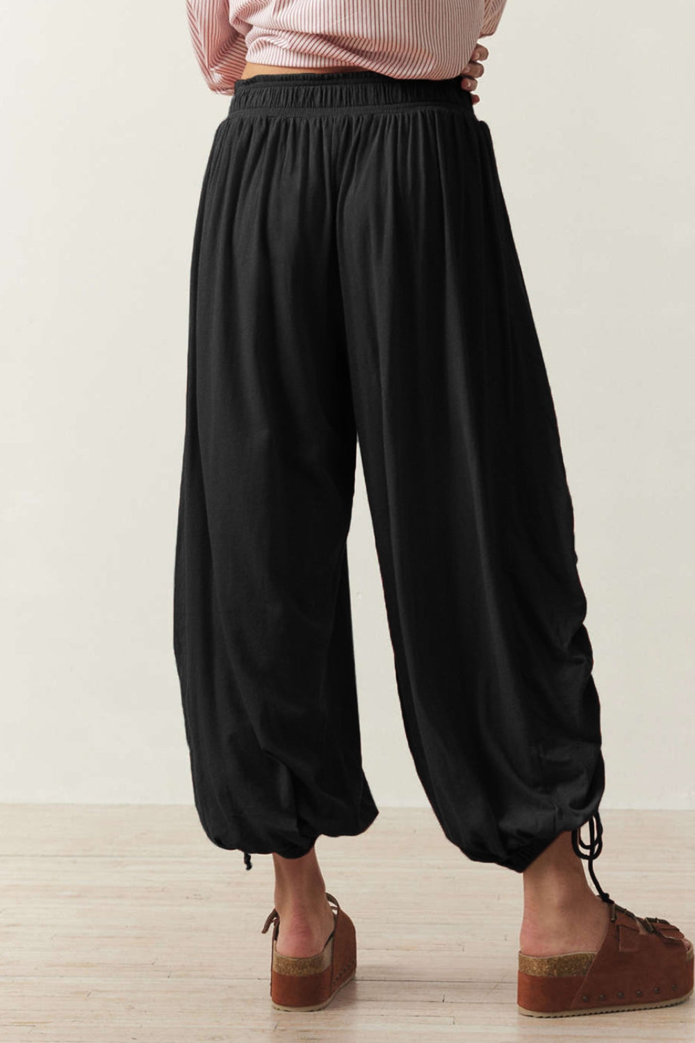 Black gathered ankle-tie balloon trousers with a drawstring detail at the ankle.