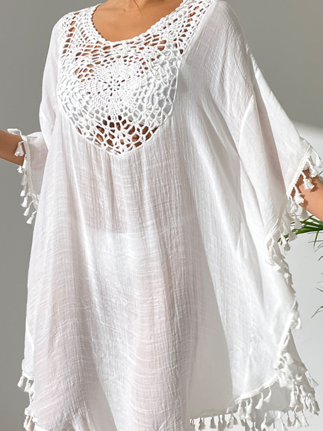 White crochet yoke tassel kaftan dress with sheer fabric and fringe trim.