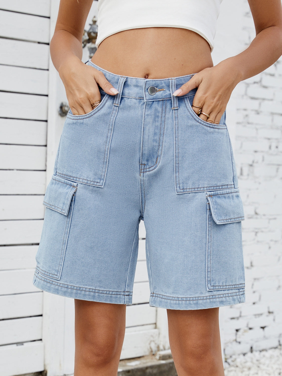Light blue denim Bermuda cargo shorts with multiple pockets and contrast stitching.