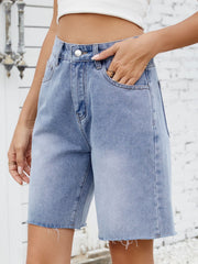 Longline denim shorts in medium wash with raw hem detail.