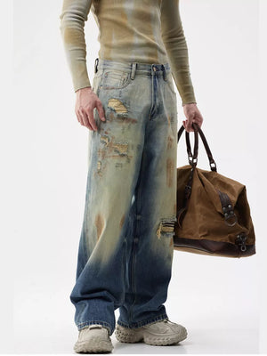Men's distressed wide-leg jeans in light blue denim with heavy fading and rips.