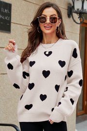 Beige knit sweater with black heart pattern, crew neck, and balloon sleeves.