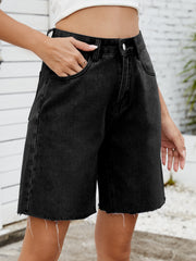 Black longline denim cutoff shorts with raw hem detail.
