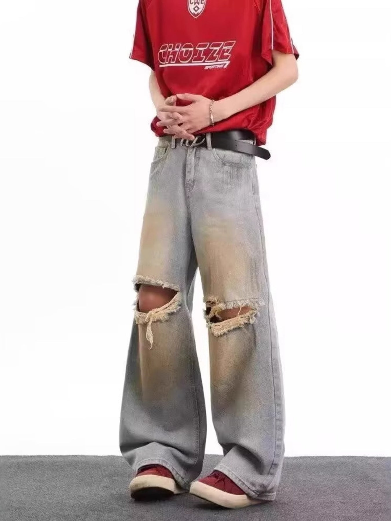 Men's blue distressed wide leg jeans with ripped knees and faded wash.