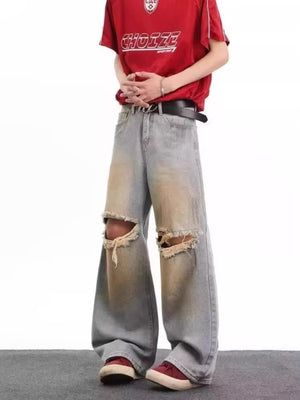Men's blue distressed wide leg jeans with ripped knees and faded wash.