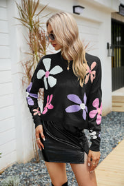 Black acrylic sweater with colorful daisy motif, drop shoulder, and crew neck.