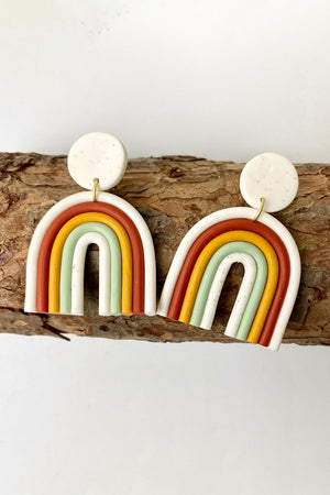 Rainbow arch clay earrings in white, rust, yellow, green, and ivory.
