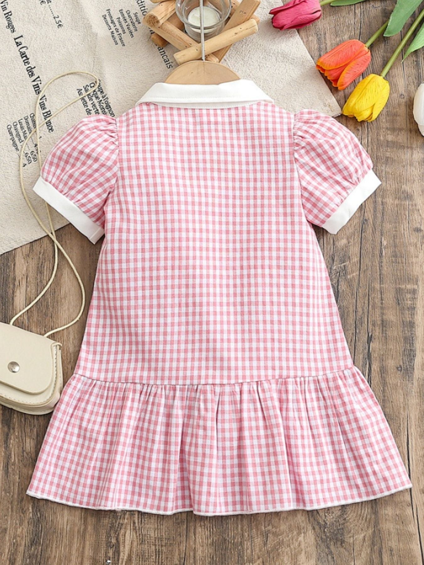 Baby pink gingham cotton polo dress with short puff sleeves and ruffle hem.