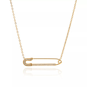 Gold layered necklace with a diamond-accented safety pin pendant.