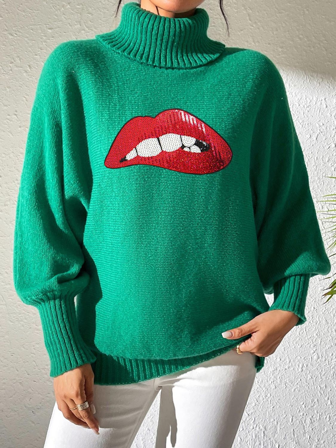 Green turtleneck sweater with sequin red lips detail and balloon sleeves.