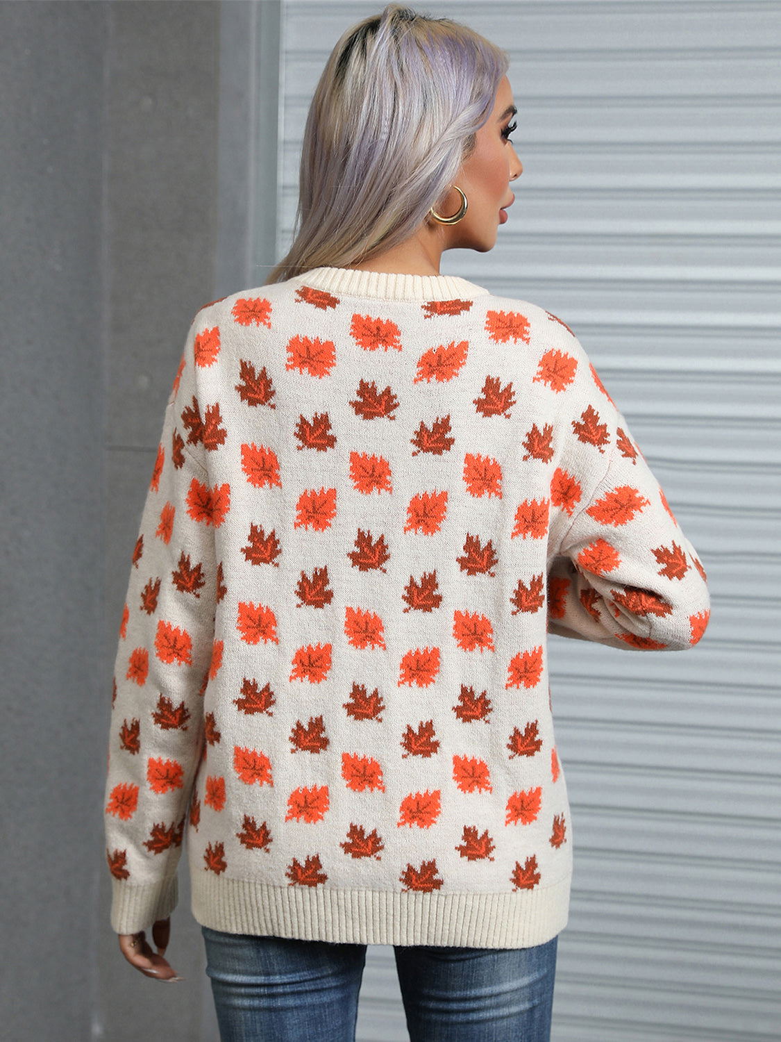 Cream knit crewneck sweater with allover orange and brown autumn leaf pattern.