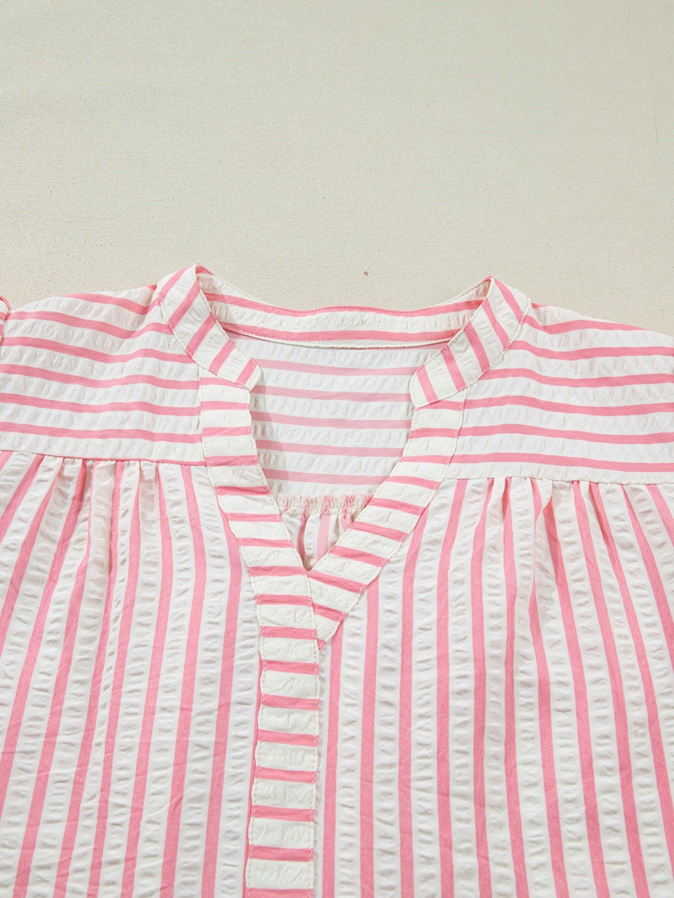 Pink and white striped seersucker blouse with V-neck and gathered yoke.