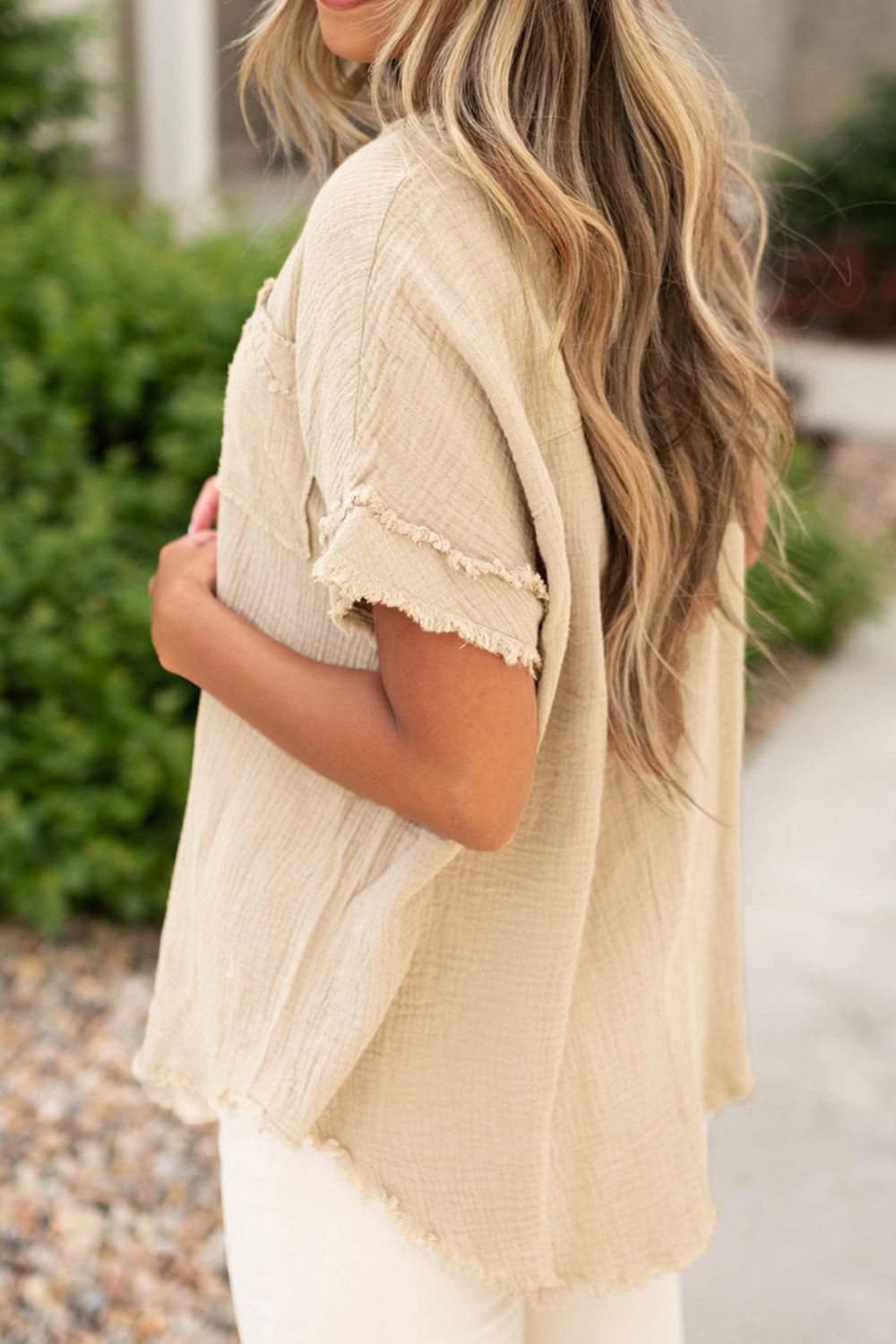 Beige textured gauze henley blouse with raw edge details and short sleeves.