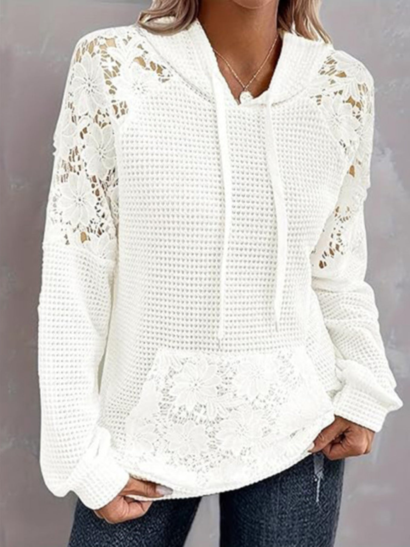 White waffle knit hoodie with floral lace sleeves and pocket detail.