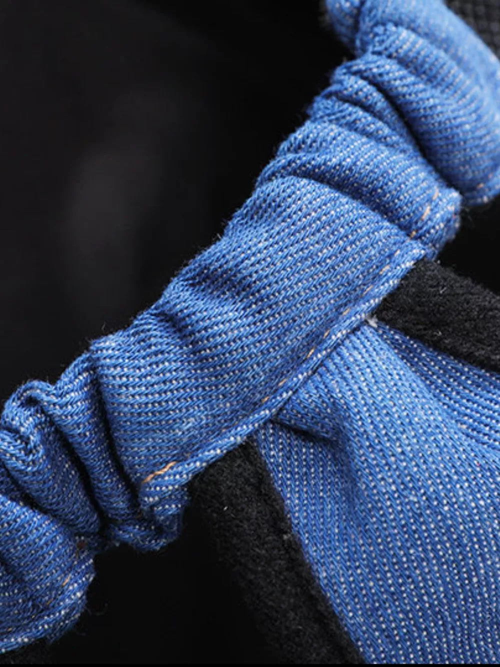 Blue denim-like pet carrier backpack strap detail with black fabric.