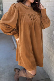 Caramel corduroy mini dress with puff sleeves, gathered neckline, and buttoned cuffs.