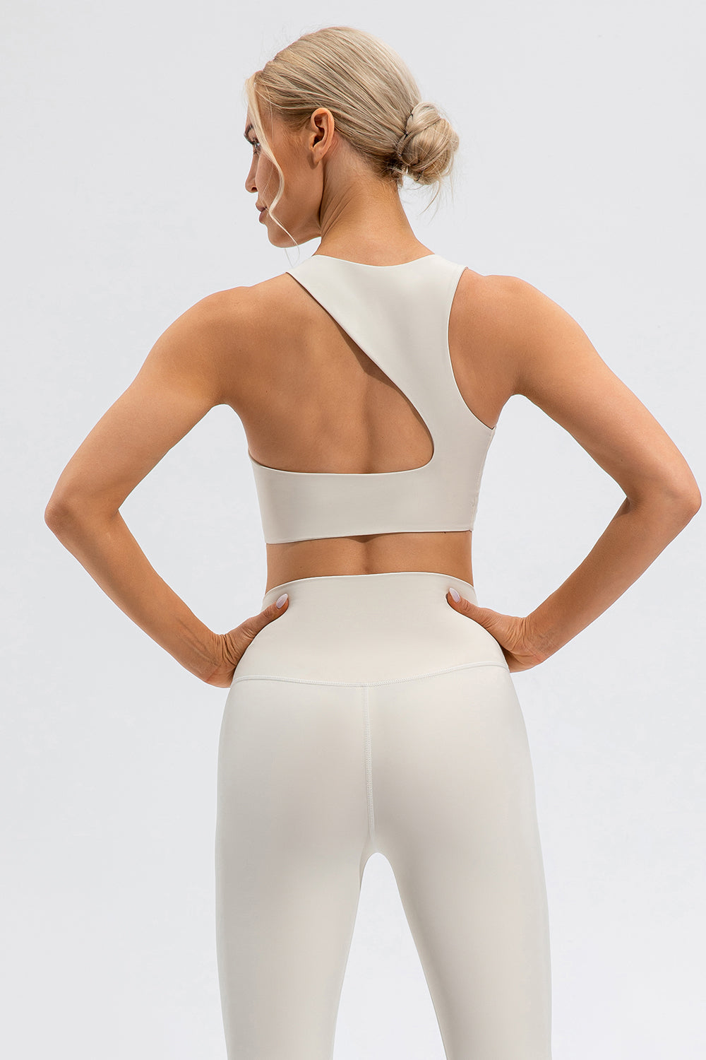 Camel sports bra with asymmetric cutout detail on back and matching high-waisted leggings.