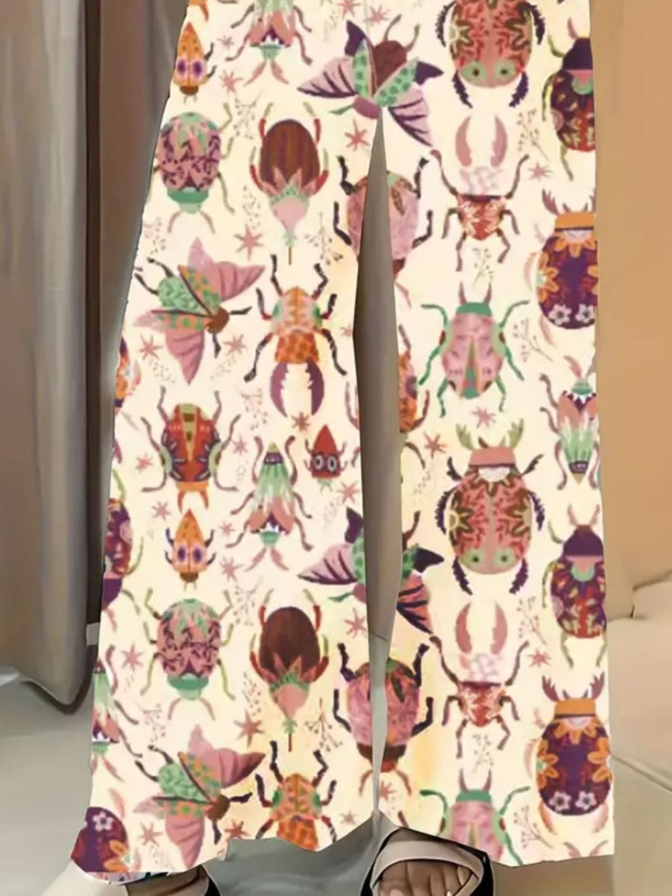 Whimsical print wide-leg maternity trousers in pastel yellow with colorful beetle and butterfly pattern.