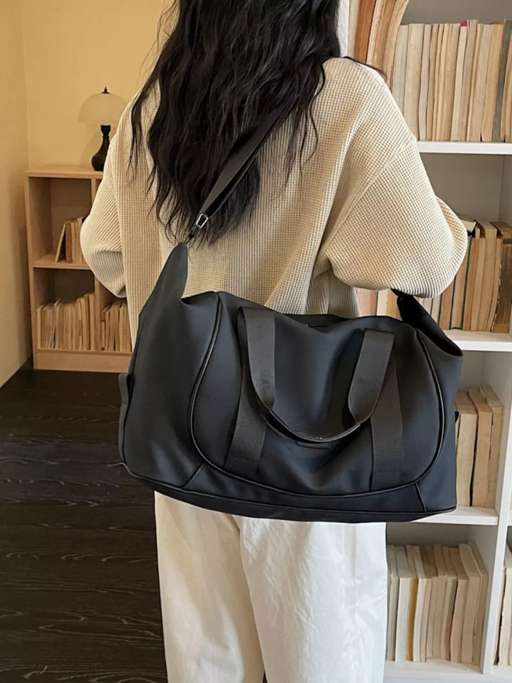 Black medium nylon travel duffle bag with curved stitching and adjustable strap.