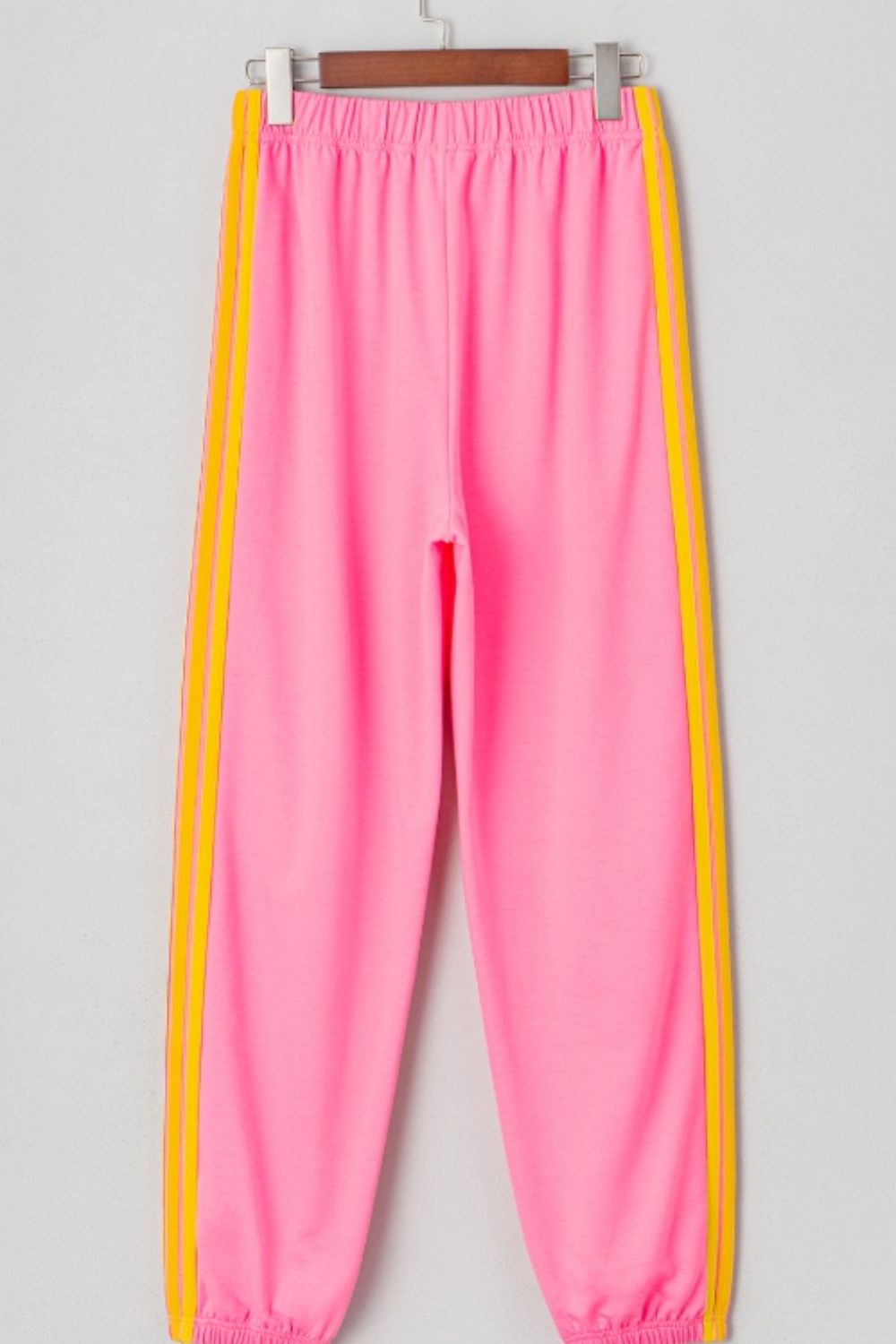 Pink track pants with yellow double stripes down the sides.