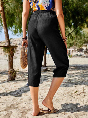 Black cropped denim trousers with elastic waist and cuffed hem.