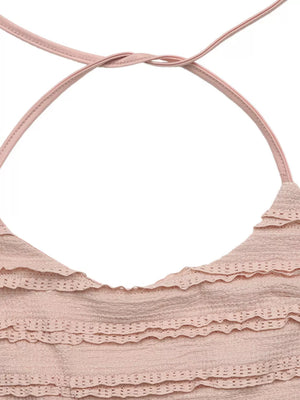 Pink textured halter neck romper with ruffled tiers and crisscross straps.
