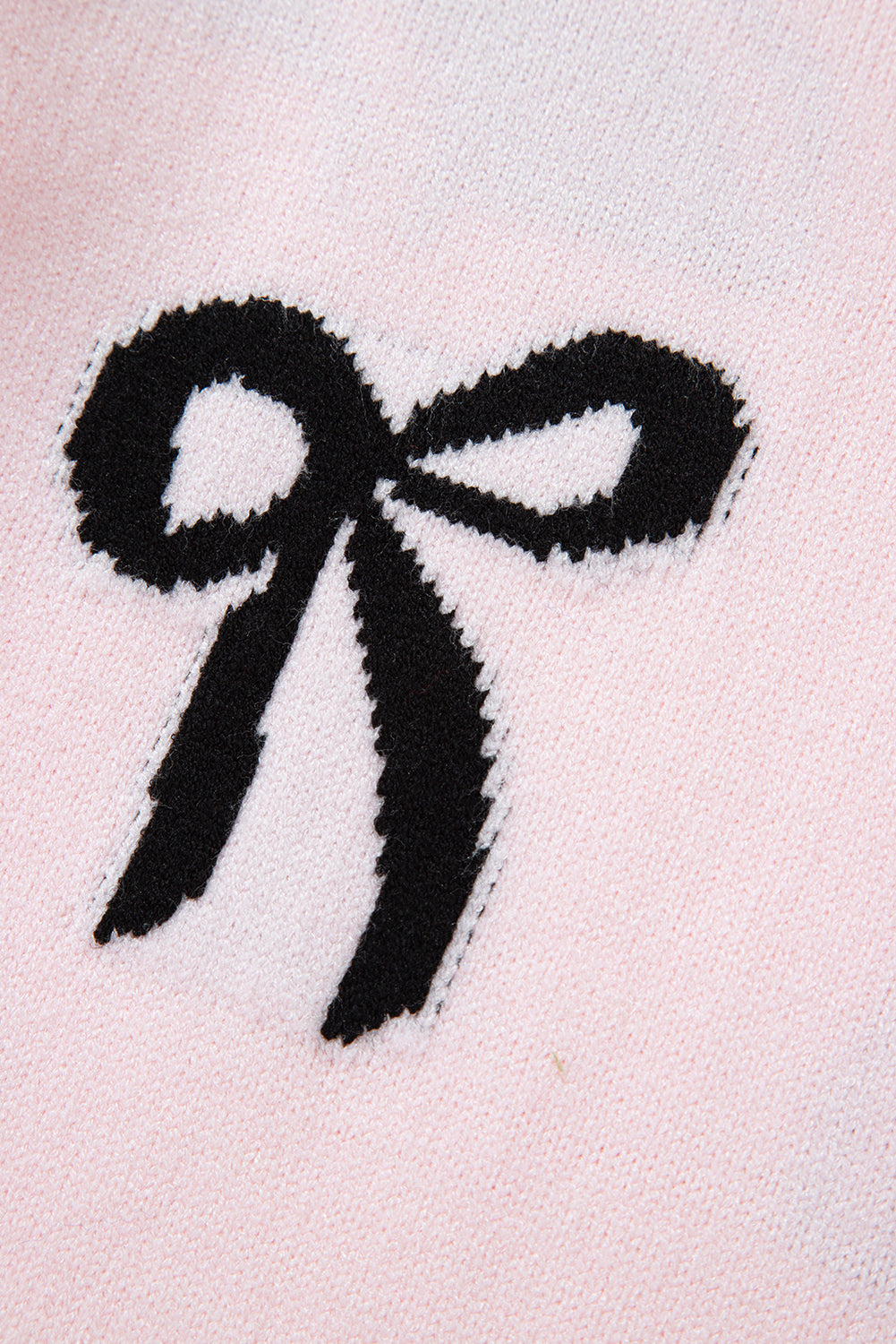 Blush pink knit sweater with a black bow motif detail.