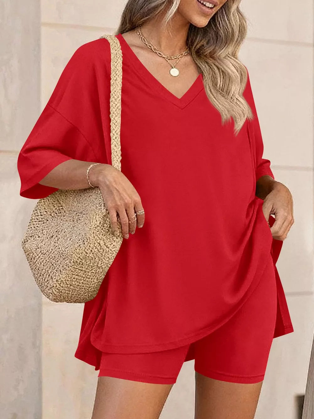 Red V-neck two-piece set with loose fit top and biker shorts, styled with a straw bag.