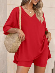 Red V-neck two-piece set with loose fit top and biker shorts, styled with a straw bag.