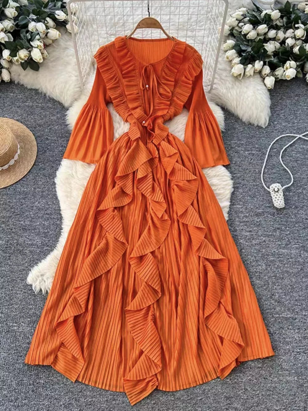 Orange midi dress with cascading ruffles, bell sleeves, and tie neck.