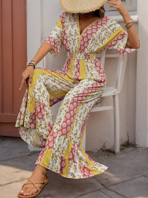 Bohemian print palazzo jumpsuit with V-neck, flutter sleeves, and ruffled wide legs in multicolor.