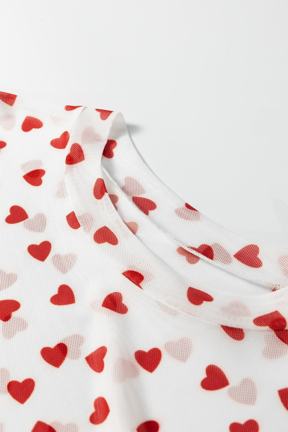 Sheer white t-shirt with red heart print and crew neck detail.