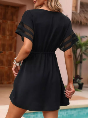 Black mini dress with V-neck, sheer striped sleeves, and cinched waist.