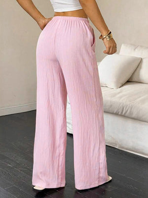 Pink crinkled wide leg pants with drawstring waist and pockets.