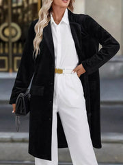Black longline trench coat with lapel collar and buttoned front, worn by a woman.