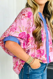 Pink floral v-neck blouse with blue striped cuffs and placket accent