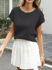 Black openwork knit short sleeve top with crew neck, styled with a white pleated skirt.