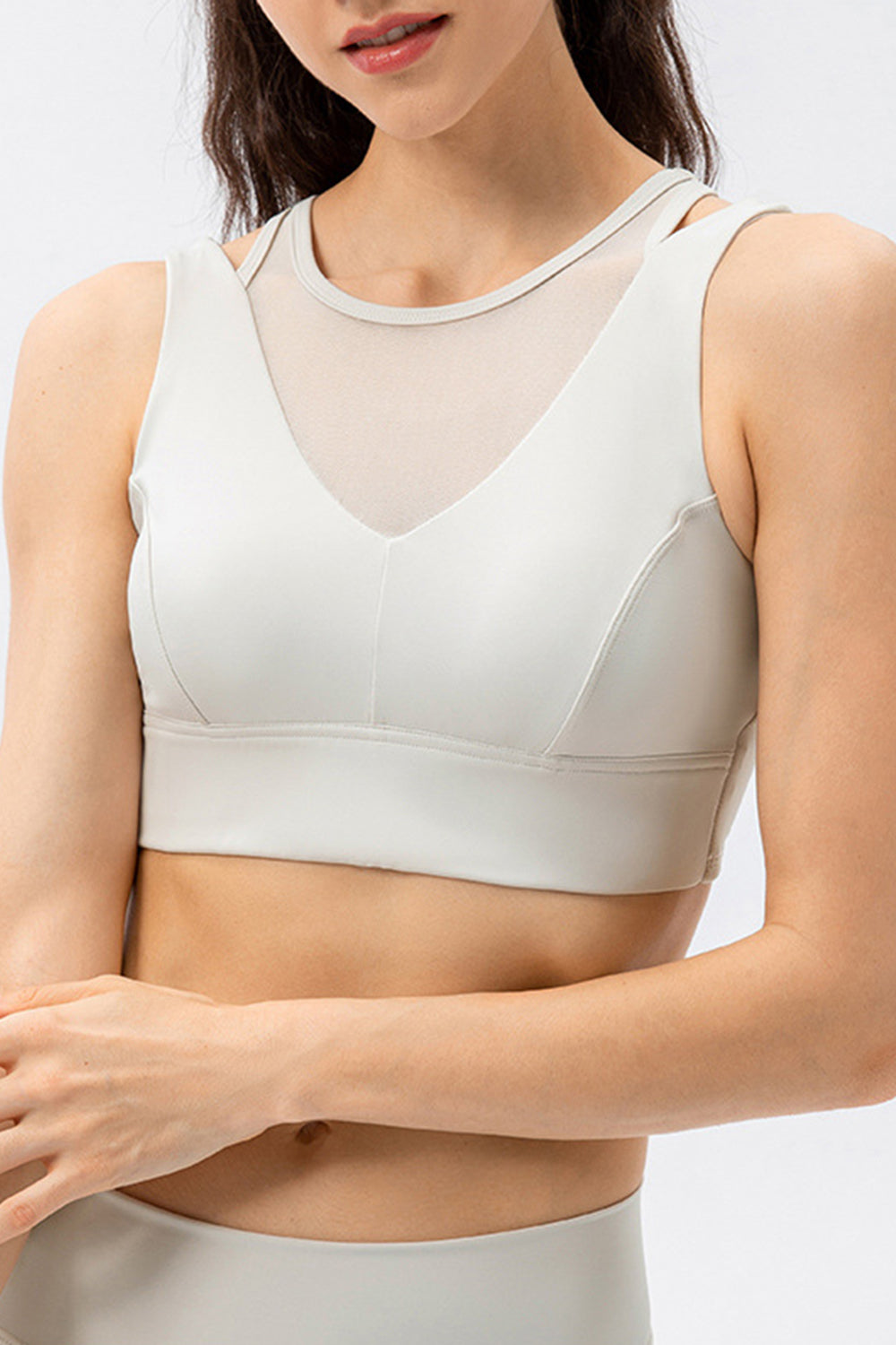 Mesh inset performance bra top in white with V-neck and double strap detail.