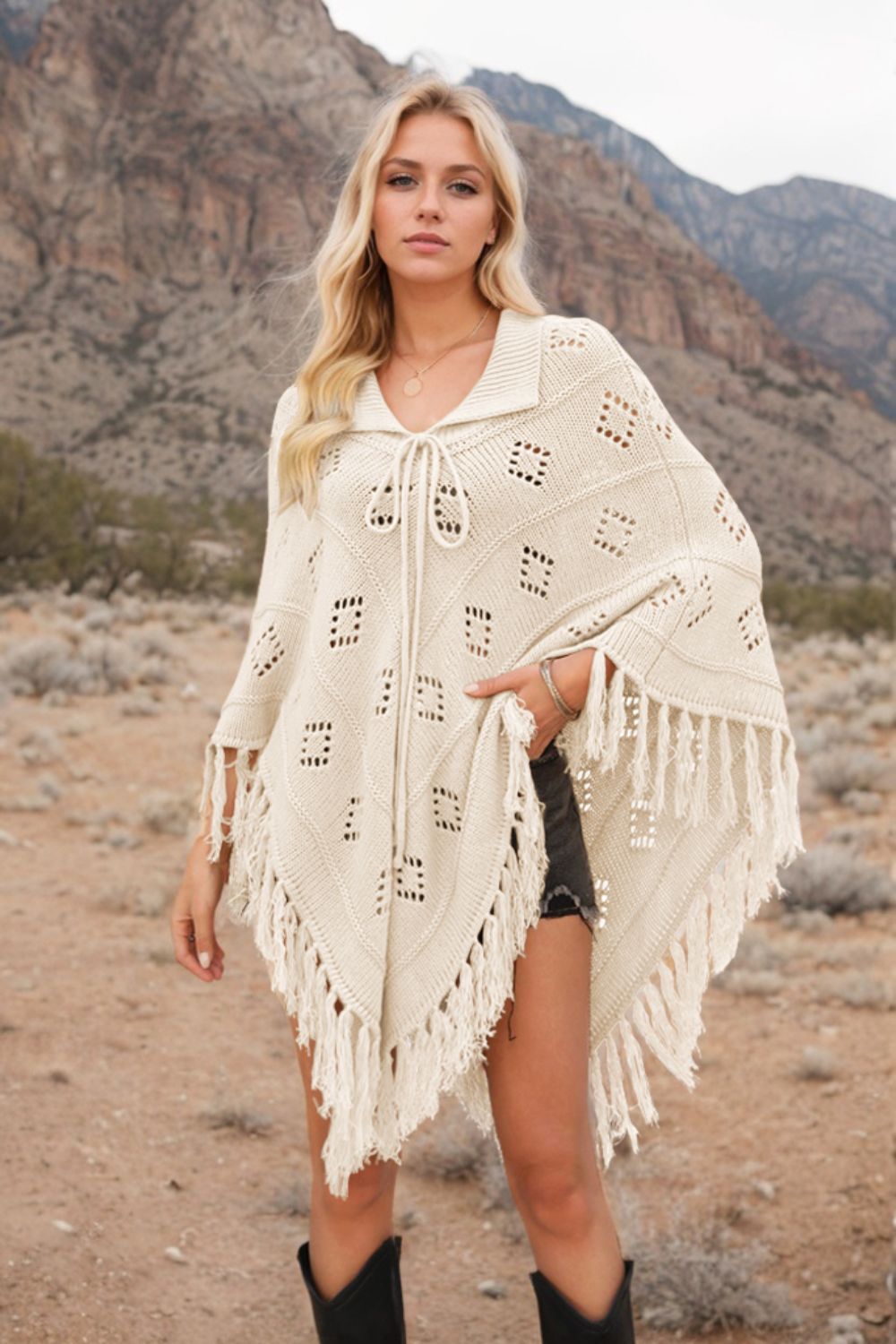 Cream knit poncho with geometric pattern and fringe, tie neck, open front, acrylic.